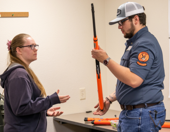 A volunteer hunter education instructor teaches a student firearm safety in a traditional hunter education course.
