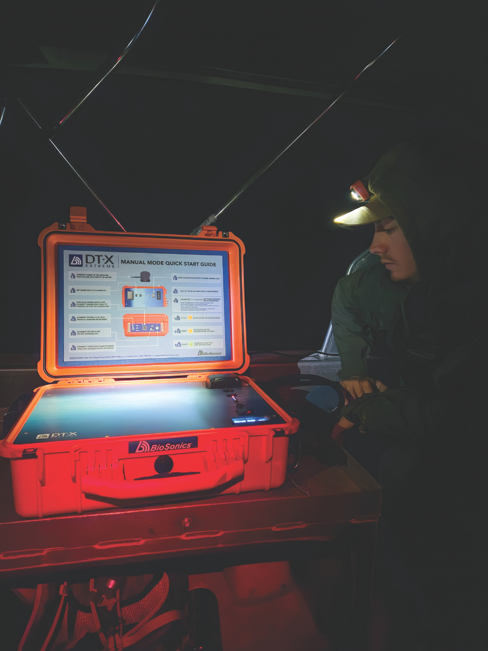 A Game and Fish biologist studies the processing box that translates information from hydroacoustic transducers to the computer