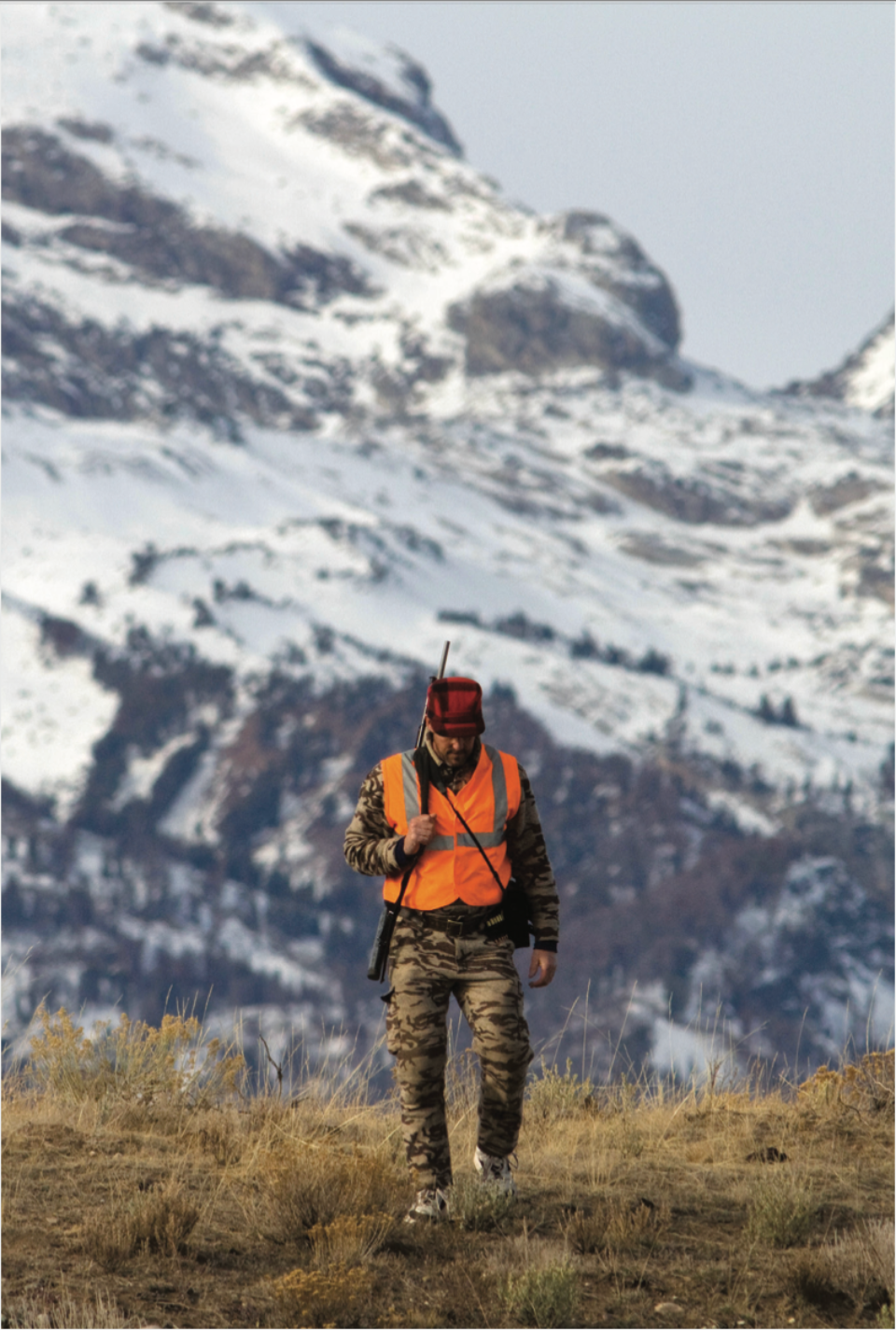 Hunter wearing hunter orange vest with rifle