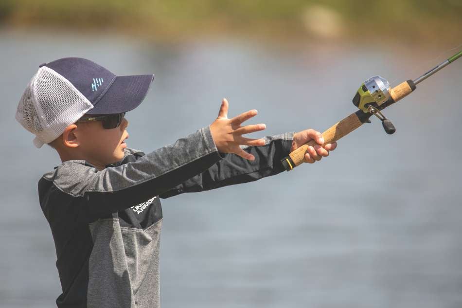 Youth Angler A youth angler in a baseball hat casts his line into the water.