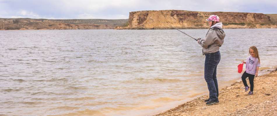 Mother and Daughter Fishing A mother and daughter fish from shore at Flaming Gorge Reservior with rocky cliffs in the background across the reservoir.