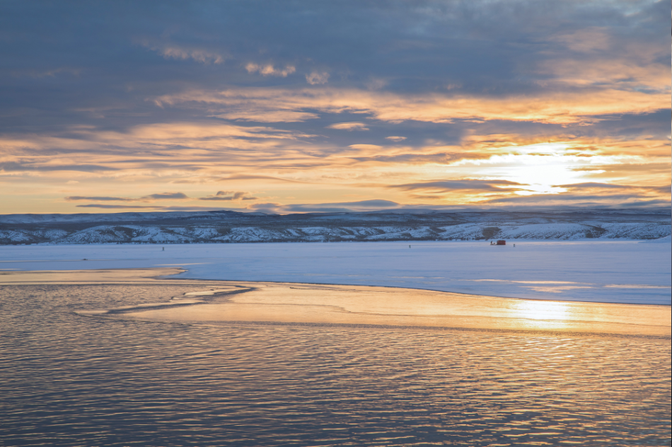 Flaming Gorge Reservoir A sunrise shines over Flaming Gorge Reservoir with ice anglers fishing on a partially ice-covered reservoir.