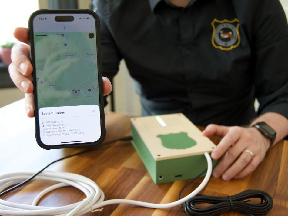 WY Game and Fish data scientist holds a phone up to demonstrate the functionality of the J* device's system check. 