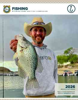 The 2026 Wyoming Fishing Regulation Brochure cover featuring a man holding a fish by the edge of a lake.