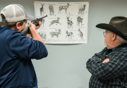 A volunteer hunter education instructor observes a hunter education student's shot placement.