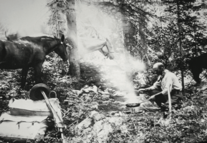 Albert Nelson, the first Wyoming game warden, cooks beside a campfire in 1899.