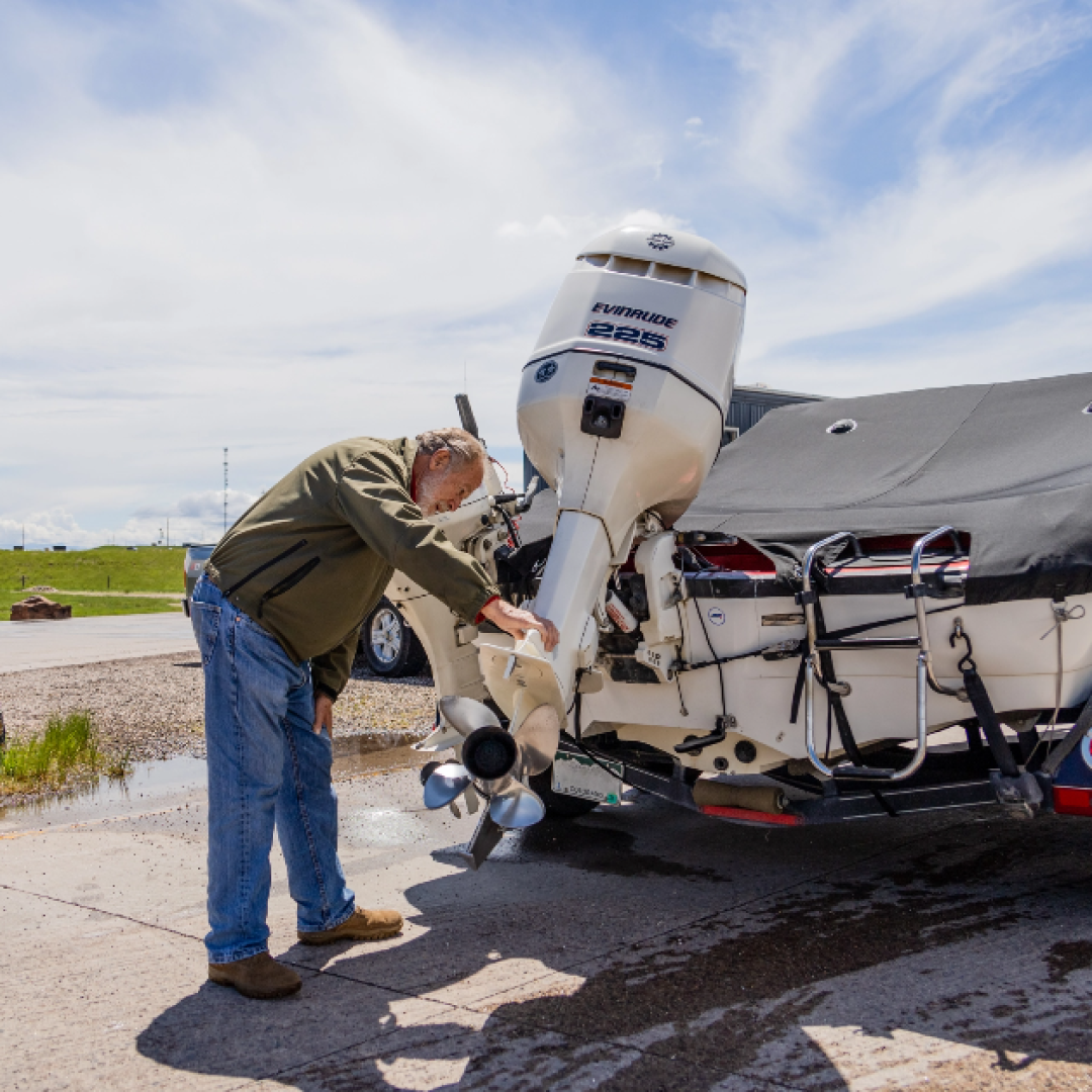 Game and Fish AIS technician checks a motor on a watercraft at a watercraft check station