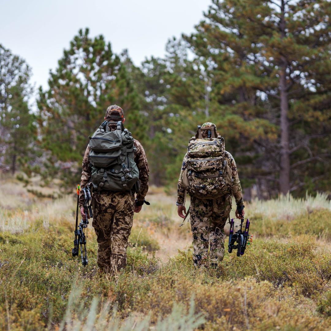 Two hunters walking towards trees in the Laramie Region.