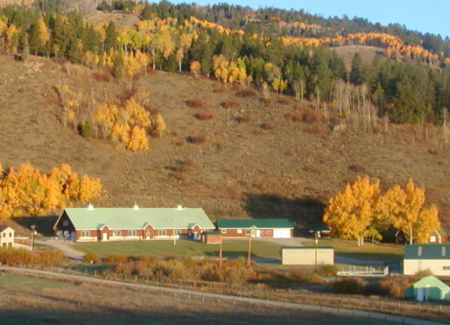 The Auburn Fish Hatchery grounds viewed from a distance on a fall day with colorful trees on a mountain in the background.