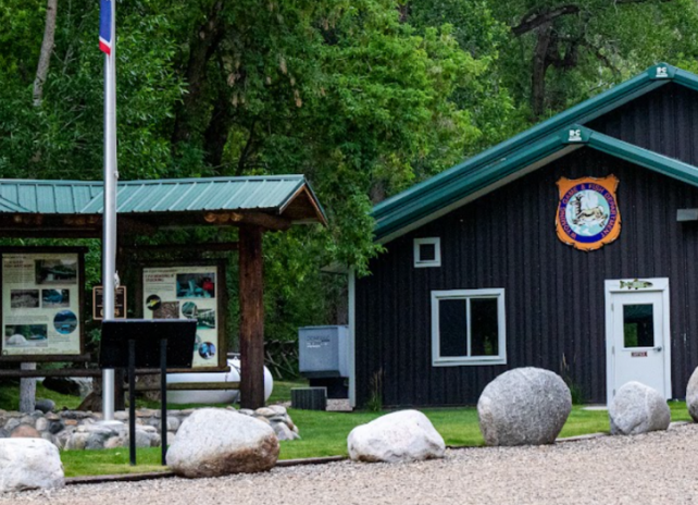 The front of the office at Ten Sleep Fish Hatchery with a visitor kiosk and flag pole.
