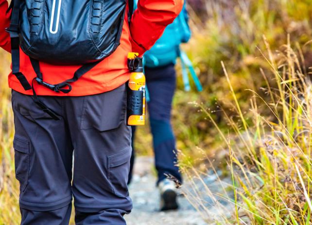 Bear spray self-defense attached to backpackers when hiking