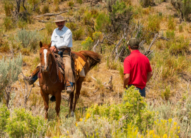 A Game and Fish warden talks to a landowner on horseback