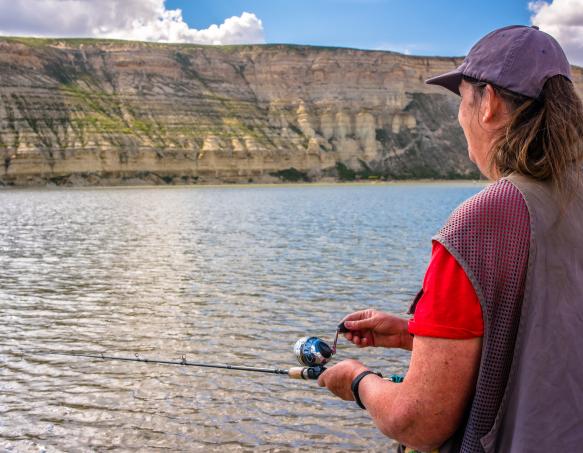 A woman fishes from the shoreline of Flaming Gorge