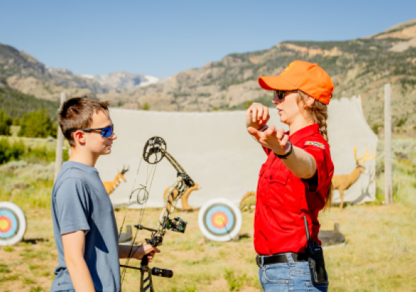 Game and Fish hunter education instructor gives archery tips to a bowhunter education student.
