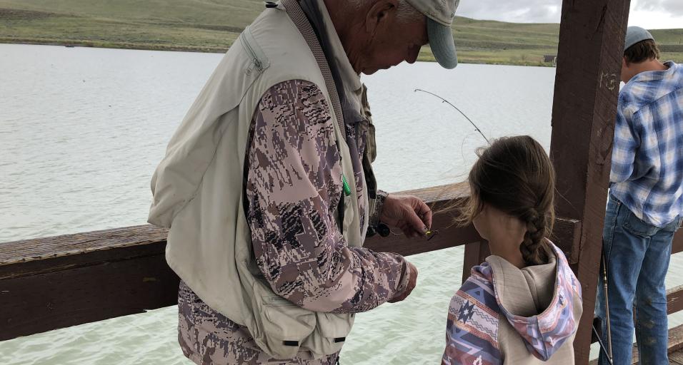 A volunteer assists a participant at the 2024 Kids Fishing Day with baiting a hook. 