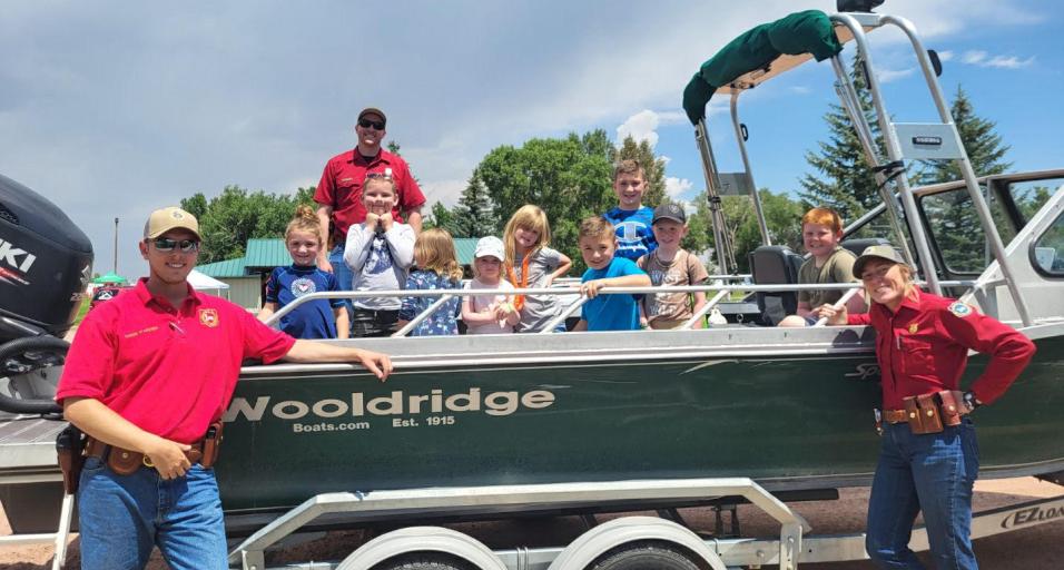 Game and Fish employees smile with a boat full of young students learning about watercraft safety.