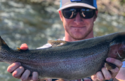 Male angler holds a large rainbow trout for a photo