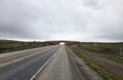 A two lane highway passes beneath a newly constructed wildlife overpass