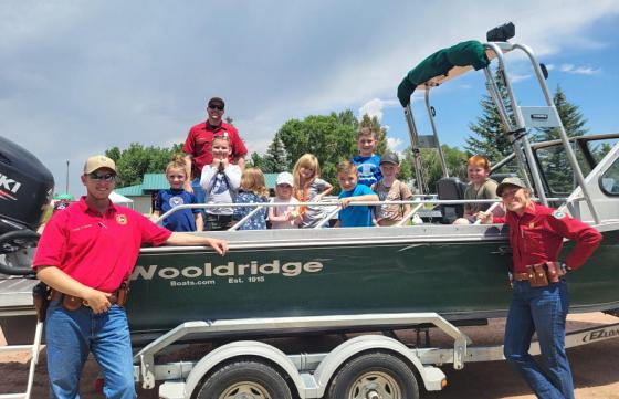 Game and Fish employees smile with a boat full of young students learning about watercraft safety.