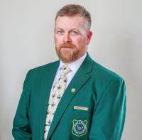 A portrait of Wyoming Game and Fish Commissioner Fonzy Haskell in a green sport coat with the Game and Fish Shield embroidered on it.