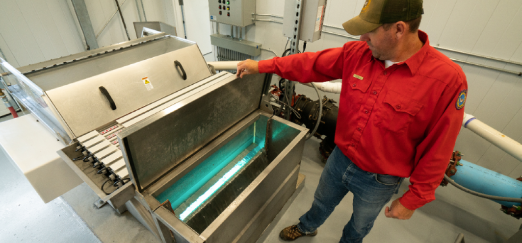 The Fish Hatchery Superintendent shows the inside of a Roto Filter UV water treatment machine used at the hatchery to treat water.
