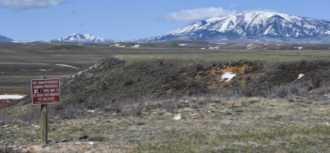 A wildlife closure sign in front of a large wildlife habitat area with snow covered mountains in the background
