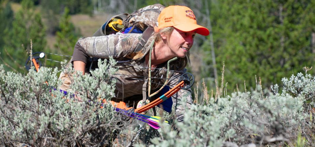 BOW participant crawling through sage brush with BOW and Arrow