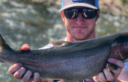 Male angler holds a large rainbow trout for a photo