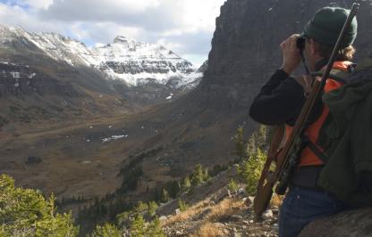 elk hunter looks through binoculars across a mountain ravine Elk Hunter glasses out on the landscape