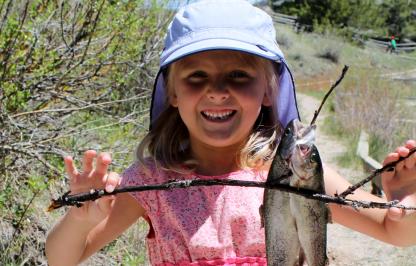 Young girl with fish on free fishing day in Dubois