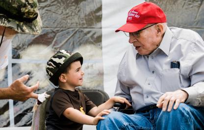 Maury Brown talks with a child who caught a rainbow trout at Kids Fishing Day