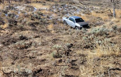 A silver pickup is stuck after driving off-road into the sagebrush.