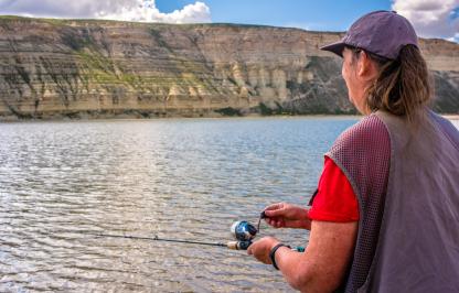 A woman fishes from the shoreline of Flaming Gorge