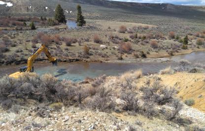 An excavator on the shore of the Big Sandy river completes work.