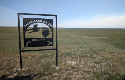 Falxa Land Co sign in front of a flat, grassy landscape. 