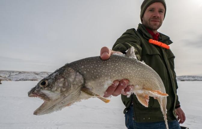 Man holding fish caught while ice fishing on Flaming Gorge Reservoir