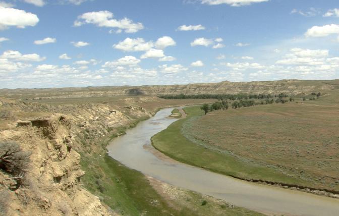 A landscape photo with a river and a small bluff.